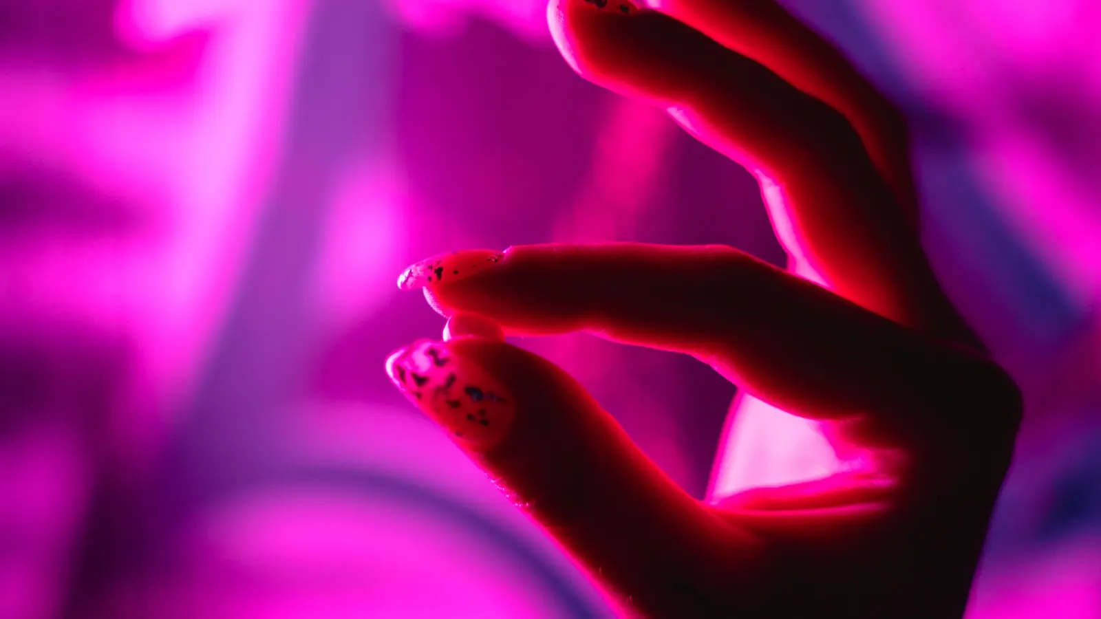 Hand med nagelkonst i rosa neonljus