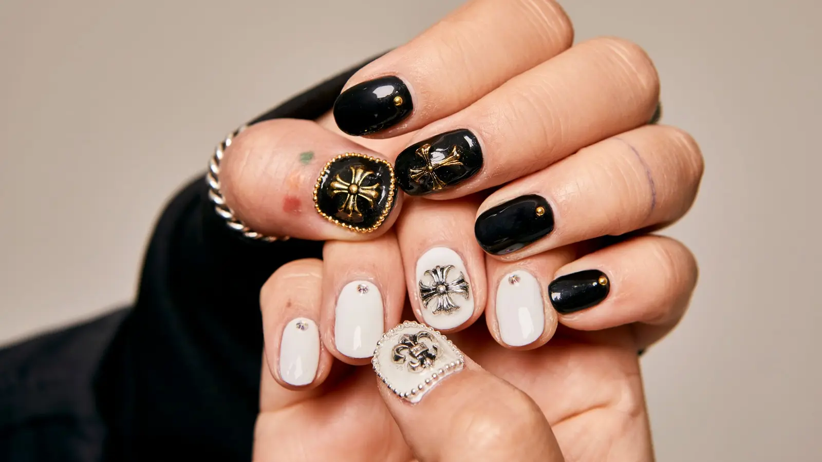 Händer med konstnärlig svartvit nageldesign och dekorativa detaljer
